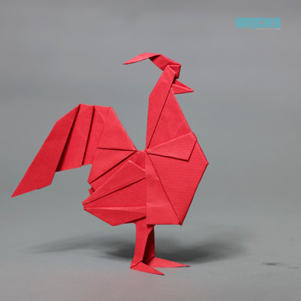 A red origami rooster placed on the south of a work desk.